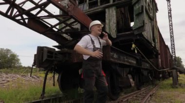 Eski demiryolu makinaları yakınındaki telefonda konuşurken demiryolu çalışanı