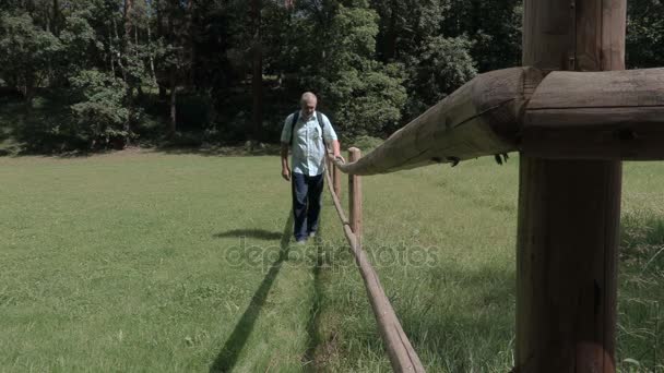 Turysta na łące w pobliżu ogrodzenia drewniane — Wideo stockowe