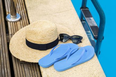 Flip flop ve Yüzme Havuzu yakınındaki güneş gözlüğü ile hasır şapka
