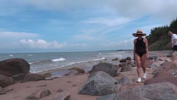 Люди на скалистом пляже у моря — стоковое видео