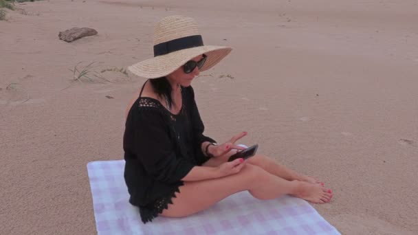 Vrouw met behulp van slimme telefoon op het strand in de buurt van de zee — Stockvideo