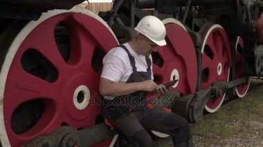 Oturma ve trenin yanında akıllı telefon kullanarak Railwayman