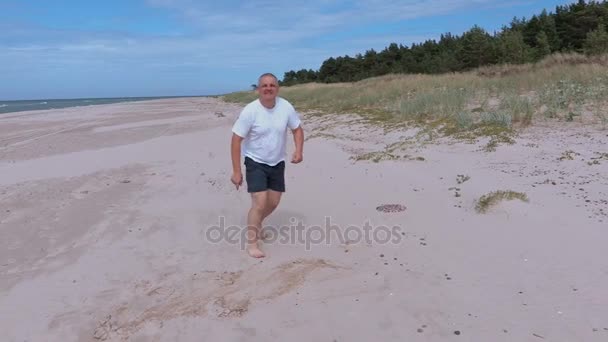 Homem jogando com disco Frisbee na praia perto do mar — Vídeo de Stock