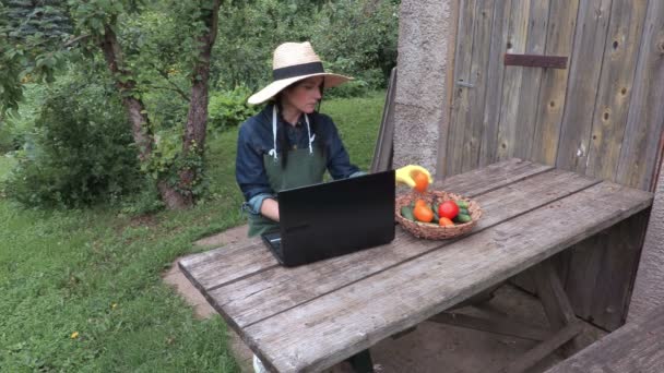 Jardinière près d'un ordinateur portable vérifiant les légumes — Video