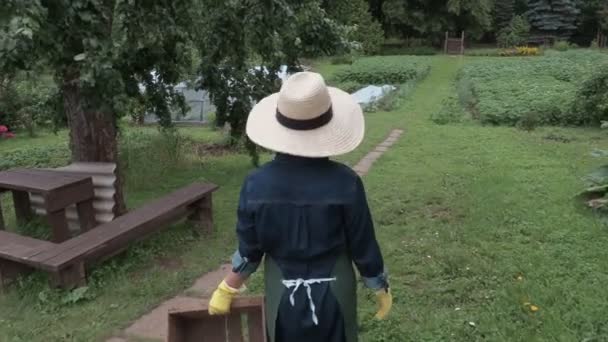 Камера следит за садовницей с деревянной коробкой — стоковое видео