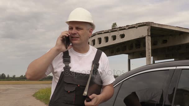 Ingenieur gesprekken over de telefoon en gaat in de auto — Stockvideo