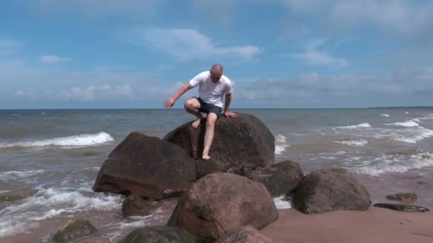 在海边的石头上受伤的人 — 图库视频影像