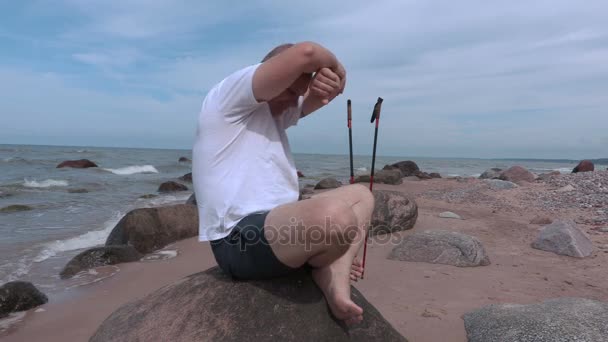 Homem faz exercícios de alongamento perto do mar — Vídeo de Stock