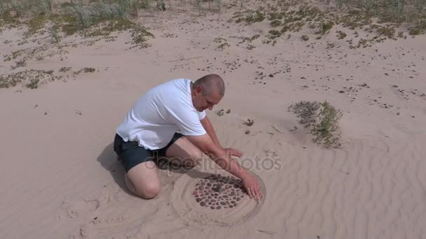 L'homme forme des marques sur la plage dans le sable — Video