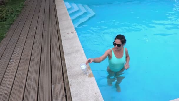 Kvinna med en cocktail vid kanten av poolen — Stockvideo