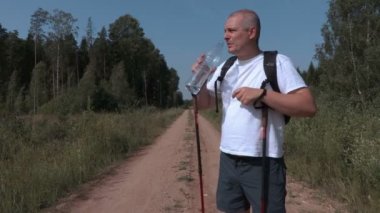 Yorgun uzun yürüyüşe çıkan kimse kırsal yolda su şişe