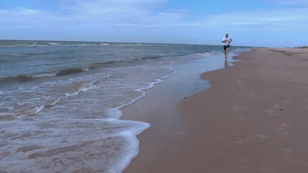 Mann läuft barfuß am Meer entlang — Stockvideo