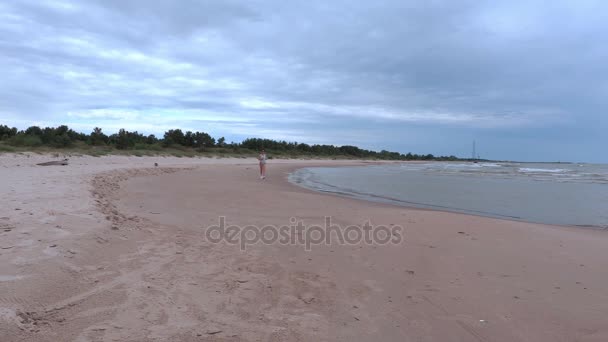 Женщина медленно бегает по песчаному пляжу — стоковое видео