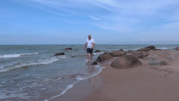 Man met blote voeten lopen in de buurt van de zee — Stockvideo