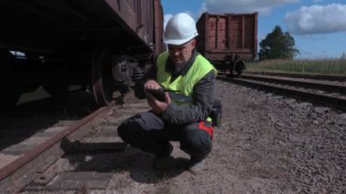 Demiryolu işçisi vagon tekerlekleri yakınındaki tablet kullanma