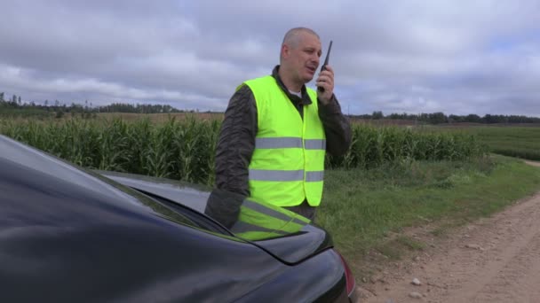 Фермер использует рацию рядом с кукурузным полем — стоковое видео