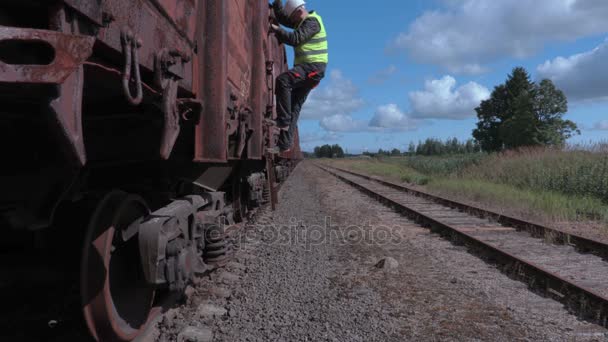 Trabalhador ferroviário usando tablet e caminhando perto de vagões — Vídeo de Stock