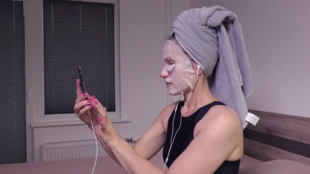 Mujer con máscara facial usando teléfono inteligente — Vídeo de stock