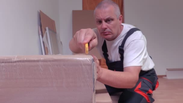 Cámara enfocada en cuchillo y desembalaje caja de muebles — Vídeo de stock