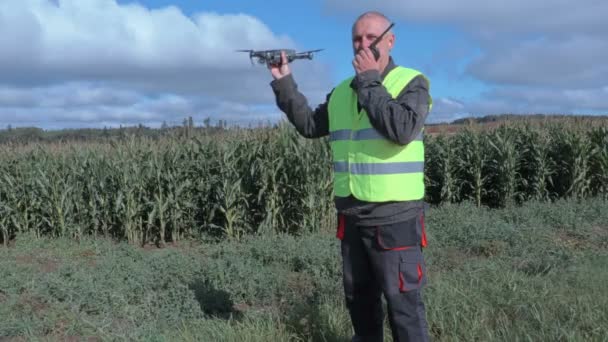 Boer met drone en walkie talkie bij maïsveld — Stockvideo