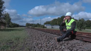 Raylar üzerinde oturan ve tablet ve walkie talkie kullanarak demiryolu işçisi