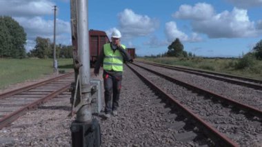 Yürüyüş ve vagonlar yakınındaki telefonda konuşurken demiryolu çalışanı