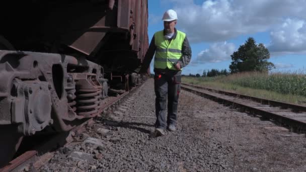 Железнодорожный рабочий осматривает вагонные колеса — стоковое видео