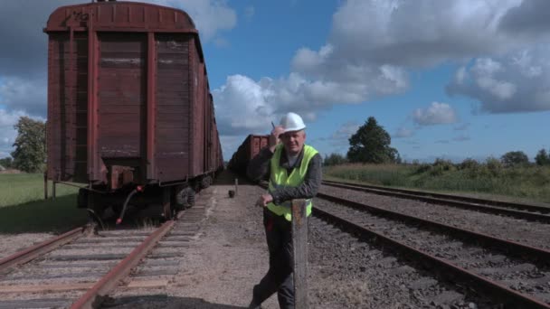 Funcionário ferroviário mostrando gestos de parada perto de vagões — Vídeo de Stock
