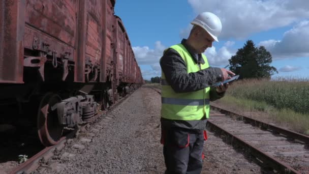 Empleado ferroviario usando teléfono inteligente cerca de vagones — Vídeos de Stock