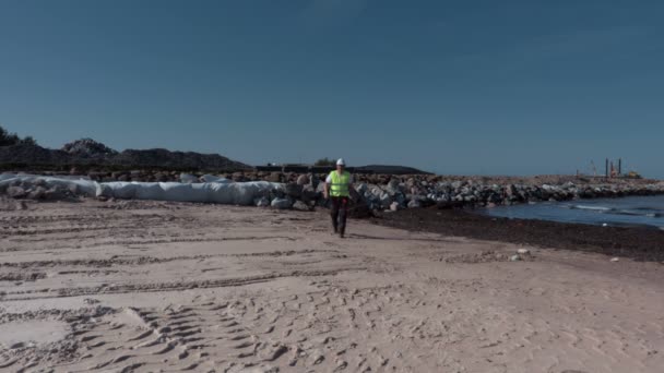 Constructor caminando en el sitio de construcción cerca del muelle — Vídeo de stock