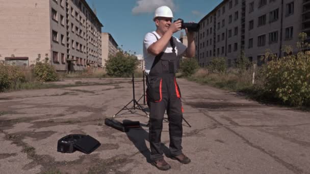 Bauarbeiter mit Fotokamera in verlassener Stadt — Stockvideo