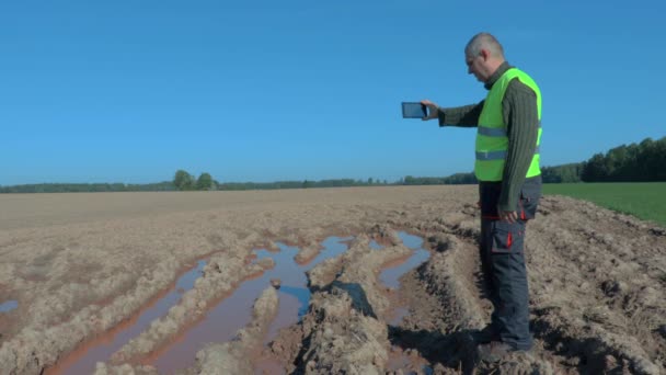 Agricultor inspeccionando el campo húmedo — Vídeos de Stock