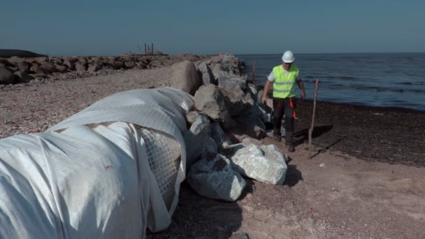 Worker inspecting stone isolation at piers — Stock Video