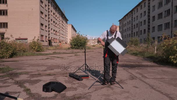 Працівник з світлодіодною підставкою біля будівель — стокове відео