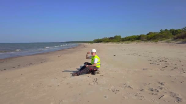 Camera vliegen over de werknemer in de buurt van de zee — Stockvideo