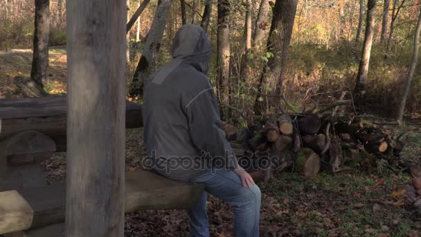 怖いハロウィーンのマスクとマチェーテの公園で座っている男 — ストック動画