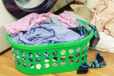 Çamaşır makinesi yakınındaki giysileri ile plastik sepet