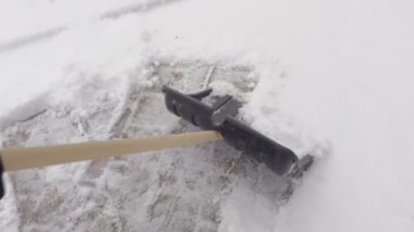 Kamera kadının kolları üzerinde kar kürekle odaklanır.