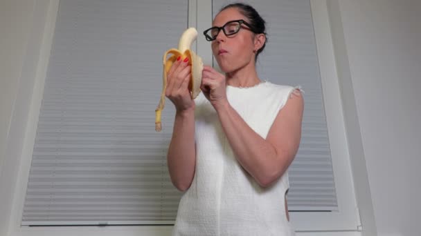 Mulher Comendo Banana Perto Janela — Vídeo de Stock