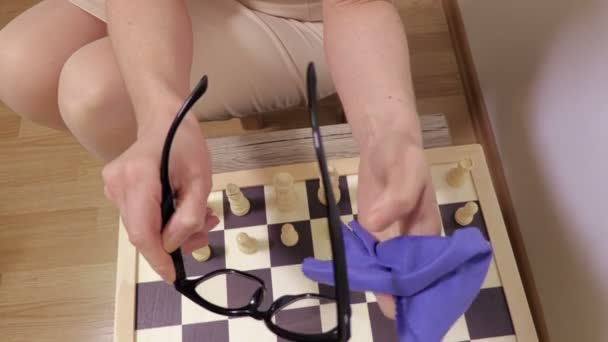 Mujer Limpiando Gafas Cerca Tablero Ajedrez — Vídeo de stock