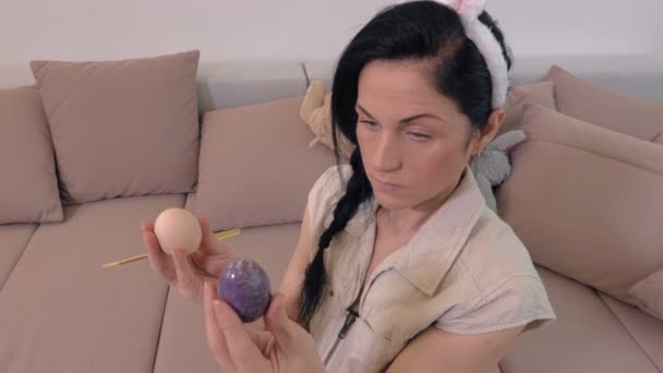 兔子耳朵保持复活节彩蛋和坐在沙发上的妇女 — 图库视频影像