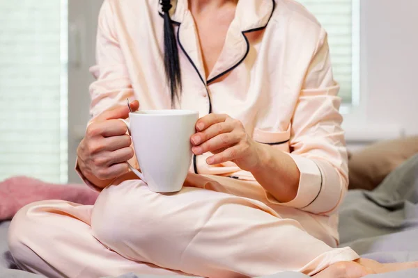 Woman in pajama drink coffee in the bed