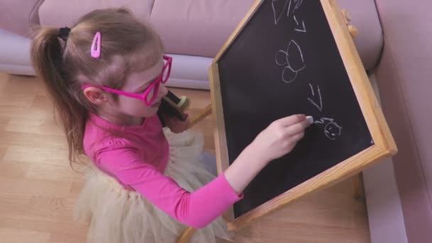 小さな女の子が黒板に人形を描画 — ストック動画