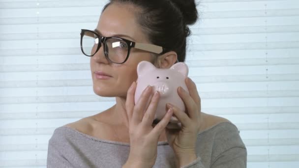 Woman holding and checking pig piggy bank