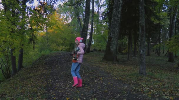 小女孩带着耳机一个人在可怕的公园里走着 — 图库视频影像