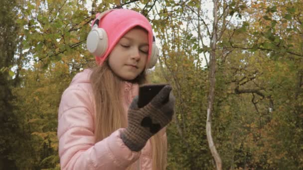 Happy Little Girl Fejhallgatóval Okostelefonnal Vezeték Nélküli Szabadság Bluetooth Technológia — Stock videók