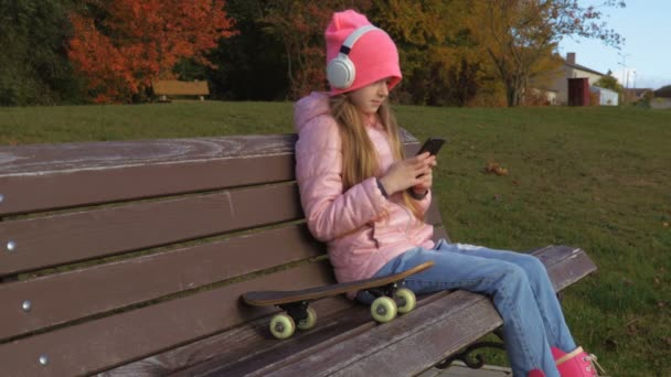 Attraktives Mädchen Mit Kopfhörern Und Skateboard Auf Bank — Stockvideo
