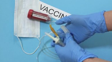Doktorun eli COVID-19 yakınlarında tıbbi ekipmanla mavi üzerinde enfekte kan örneği