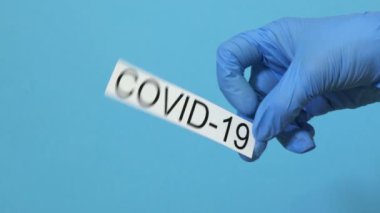 Kadın doktor mavi üzerine COVID-19 pankartı tutuyor.