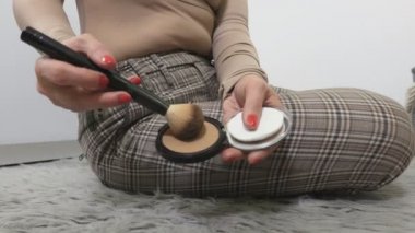 Yerde oturan ve allık süren bir kadın.